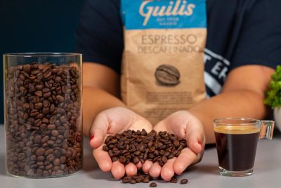 Verónica muestra los granos de café Guilis descafeinado junto a un espresso