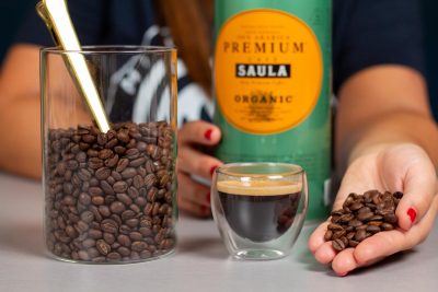 Verónica muestra en su mano los granos de café Saula junto a un espresso