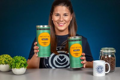 Verónica sostiene con sus manos dos latas de café en grano Saula