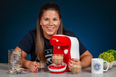 Plano general de Verónica junto a la cafetera Tassimo Happy y varias bebidas