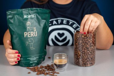 Verónica cogiendo los granos de café Perú de Incapto junto a una taza de café