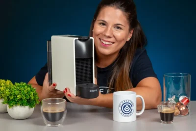 Verónica sosteniendo a la Nespresso Essenza Mini junto a varios cafés